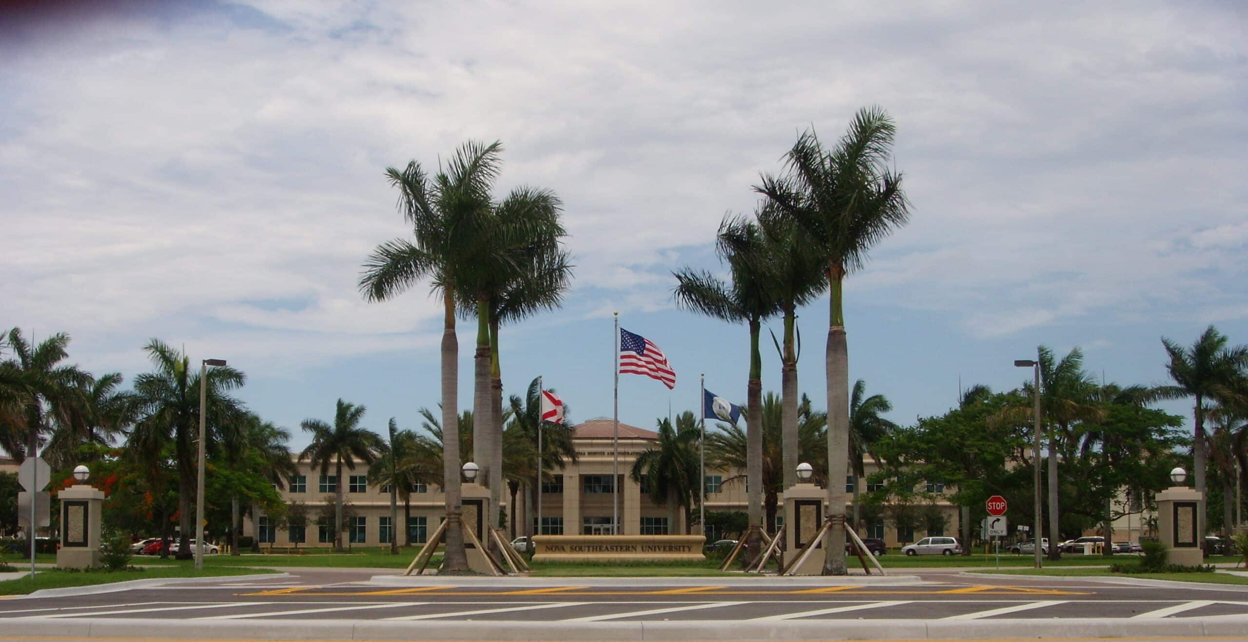 the front entrance of Nova Southeastern University, highlighted by palm trees and three flags